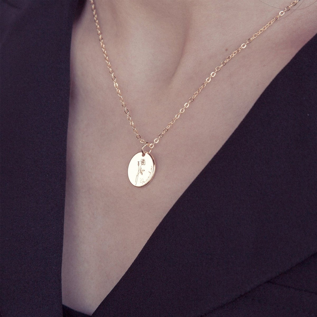 Gold necklace with a pendant on a person wearing a dark top