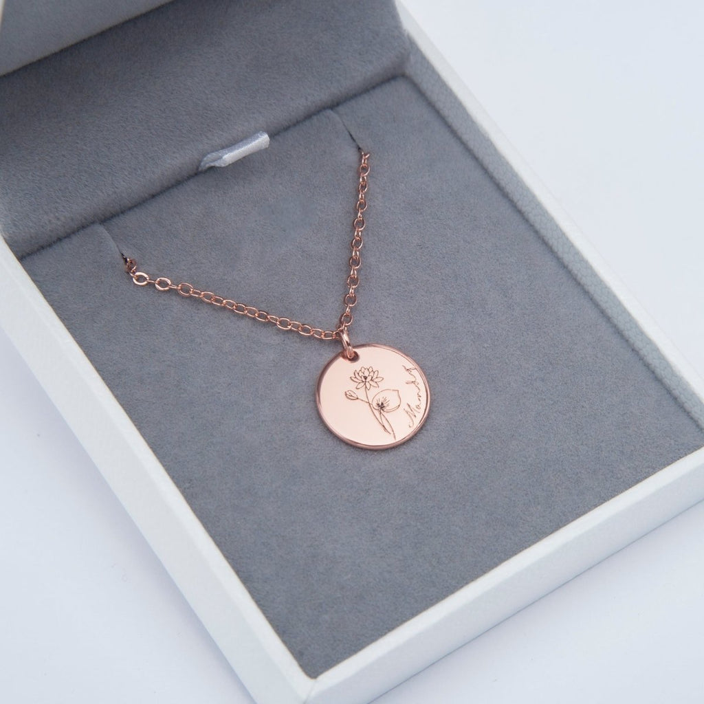 Rose gold necklace with a round pendant in an open jewelry box on a light gray background engraved memories