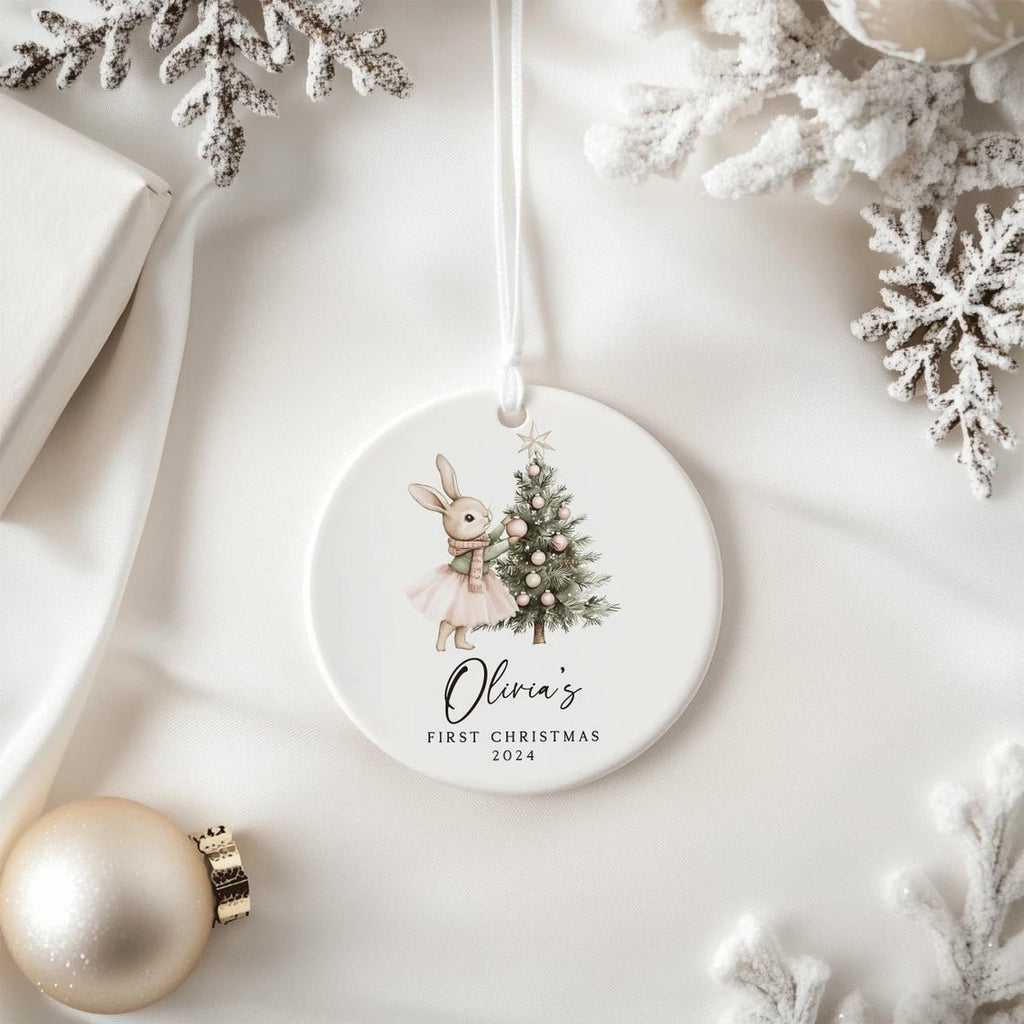 Round Christmas ornament with a rabbit and tree design, featuring 'Olivia's First Christmas 2024', on a white background with decorative elements.
