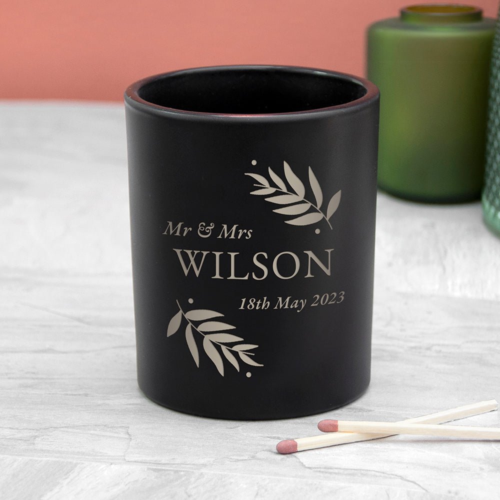 Black candle holder with 'Mr & Mrs Wilson 18th May 2023' engraving on a light surface.