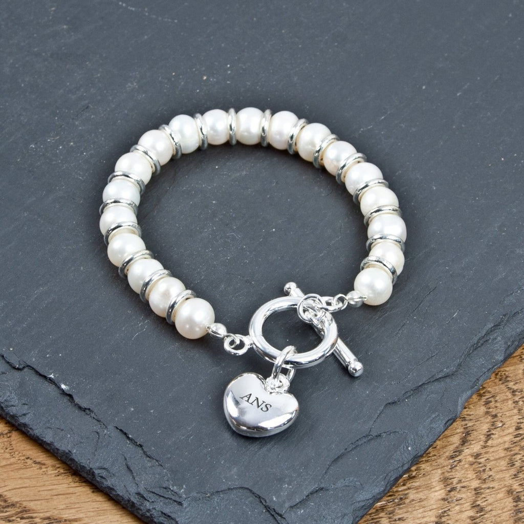Pearl bracelet with a heart-shaped charm on a dark slate surface