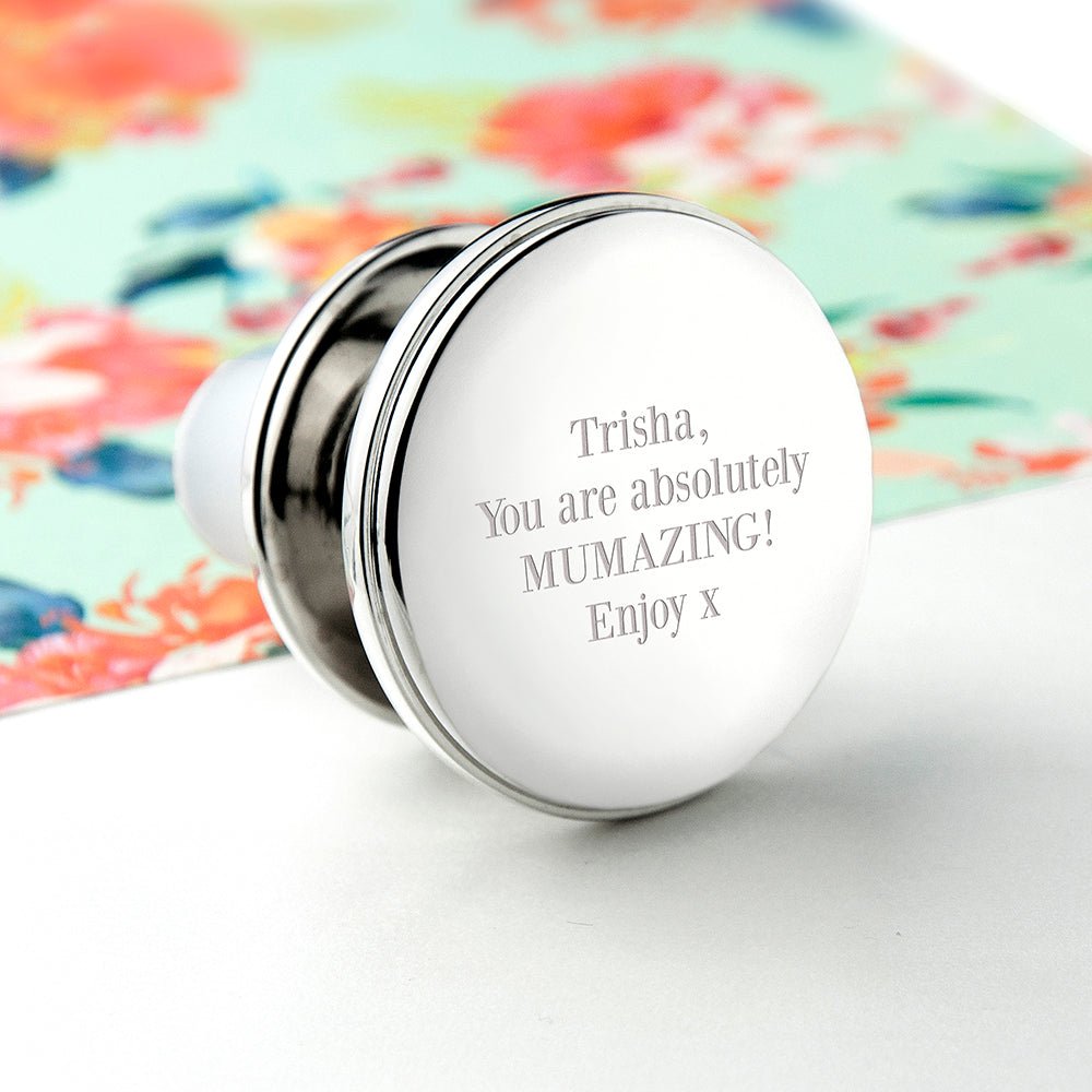 Silver container with engraved message on a colorful floral background