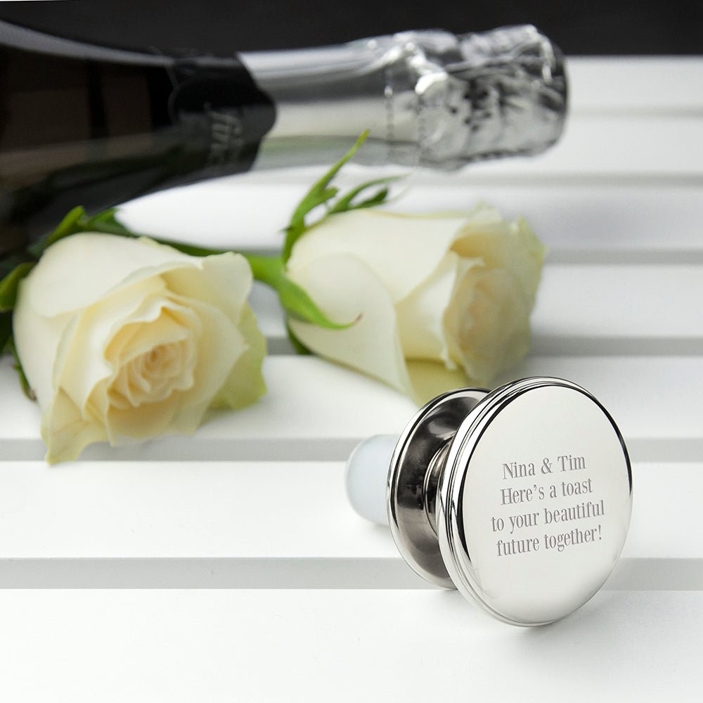 Personalized bottle stopper with engraved message next to white roses on a white surface