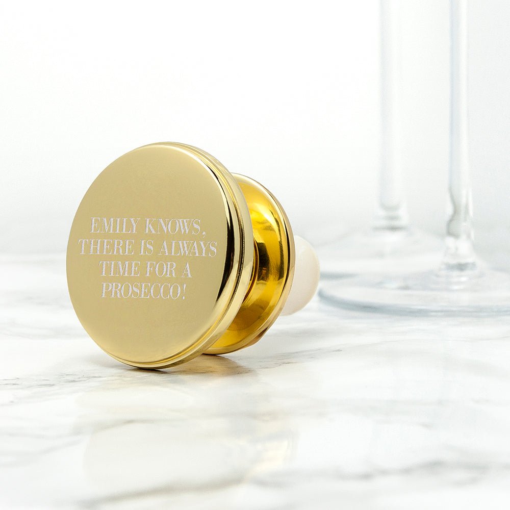 Gold bottle stopper with engraved text on a marble surface